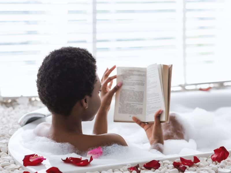 A black woman reading in her bath